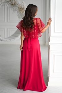 Kobieta w eleganckiej sukience na ramiączkach z cekinowym topem, stojąca w białym pokoju, twarzą do kamery.