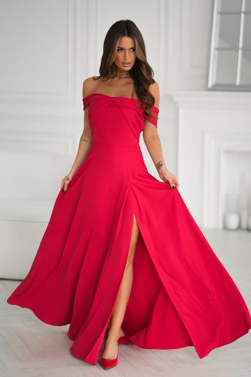 Kobieta w metalicznym połysku długiej sukni wieczorowej, bez ramiączek i długości do podłogi z wysokim rozcięciem, stojąca w pomieszczeniu na jasnej podłodze.