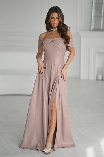 Kobieta w fioletowej sukni bez ramion z wysokim rozcięciem i metalicznym połyskiem, stojąca z gracją w białym eleganckim pokoju.