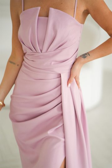 Kobieta ubrana w drapowaną różową sukienkę bez rękawów z plisowanymi detalami, pokazująca część tatuaży na ramieniu.
