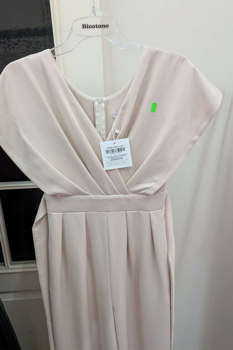 Jasnoróżowa sukienka z zakrytymi ramionami na wieszaku, z metką z ceną i zieloną naklejką, wyeksponowana na tle białej ściany — idealna na Twoje kolejne znalezisko w outlecie. Jasnoróżowa sukienka z zakrytymi ramionami na wieszaku, z metką z ceną i zieloną naklejką, wyeksponowana na tle białej ściany — idealna na Twoje kolejne znalezisko w outlecie.