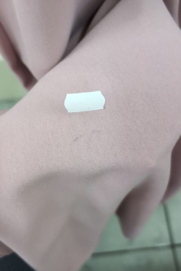 Mała biała naklejka na jasnoróżowej tkaninie Sukienka Maxi z marszczeniem w talii, na tle podłogi wyłożonej płytkami.